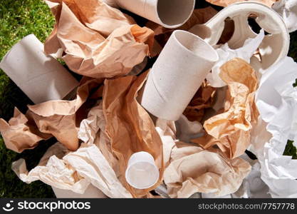 recycling, garbage disposal, environment and ecology concept - close up of crumpled paper waste on grass. close up of crumpled paper waste on grass