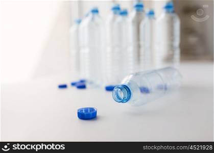 recycling, healthy eating and food storage concept - close up of empty used water bottles and caps on table
