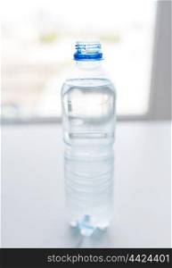 recycling, healthy eating and food storage concept - close up of open plastic bottle with pure drinking water on table