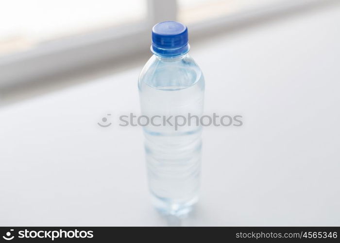 recycling, healthy eating and food storage concept - close up of plastic bottle with pure drinking water on table