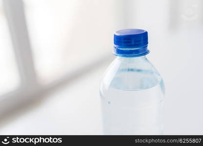 recycling, healthy eating and food storage concept - close up of plastic bottle with pure drinking water on table