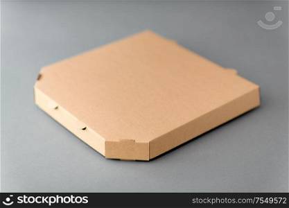 recycling, reuse and ecology concept - disposable brown takeaway food or pizza in brown paper box on grey background. takeaway food or pizza in brown paper box