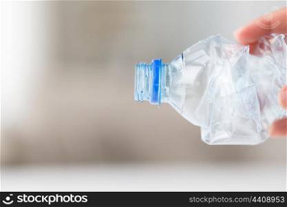 recycling, reuse, garbage disposal, environment and ecology concept - close up of hand holding used crashed plastic bottle