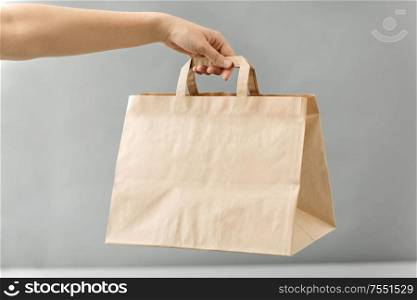 recycling, shopping and ecology concept - hand holding disposable brown takeaway food in paper bag with lunch on table. hand holding takeaway food in paper bag with lunch