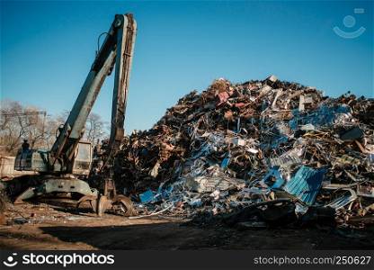 Recycling station. Metal dump with working crane and deep blue sky