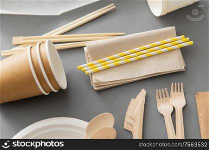 recycling, tableware and eco friendly concept - disposable dishes of paper and wood on grey background. disposable dishes of paper and wood