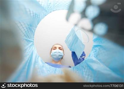 recycling, waste sorting and pandemic concept - doctor or healthcare worker in gloves throwing used medical mask into trash can with plastic. doctor throwing used medical mask into trash can