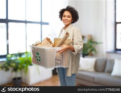 recycling, waste sorting and sustainability concept - happy smiling young african american woman holding paper garbage in plastic box over home background. happy african american woman sorting paper waste