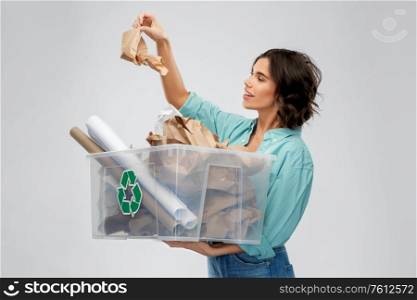 recycling, waste sorting and sustainability concept - happy smiling young woman holding paper garbage in plastic box over grey background. happy smiling young woman sorting paper waste