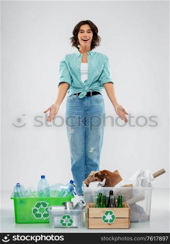 recycling, waste sorting and sustainability concept - happy smiling young woman with plastic and glass bottles, paper and metal tin cans in boxes over grey background. happy woman sorting paper, metal and plastic waste