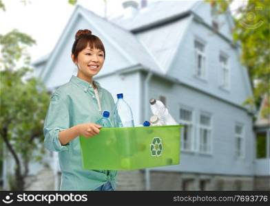 recycling, waste sorting and sustainability concept - smiling young asian woman holding box with plastic bottles over living house background. smiling young asian woman sorting plastic waste