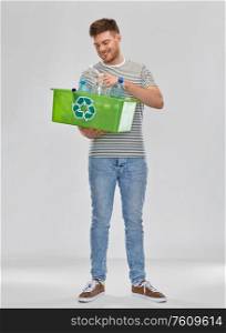 recycling, waste sorting and sustainability concept - smiling young man in striped t-shirt holding box with plastic bottles over grey background. smiling young man sorting plastic waste