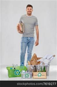 recycling, waste sorting and sustainability concept - smiling young man in striped t-shirt with plastic and glass bottles, papers and metal tin cans in boxes over grey background. smiling man sorting paper, metal and plastic waste