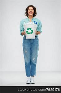 recycling, waste sorting and sustainability concept - smiling young woman in striped t-shirt holding trash bin with plastic bottles over grey background. smiling young woman sorting plastic waste