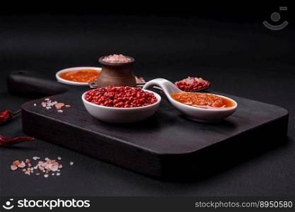 Red adjika sauce or ketchup with spices and herbs on a dark concrete background