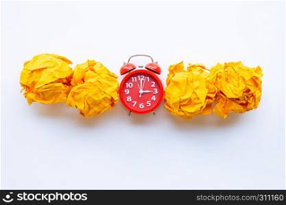 Red alarm clock ring with yellow crumpled paper ball isolated on white background.