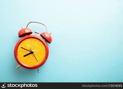 Red alarm clock with a fresh orange dial. Retro styre 'orange' clock with bells on blue background.
