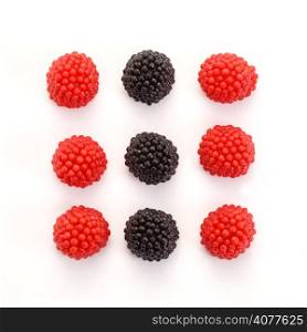 Red and black berry candy on white background