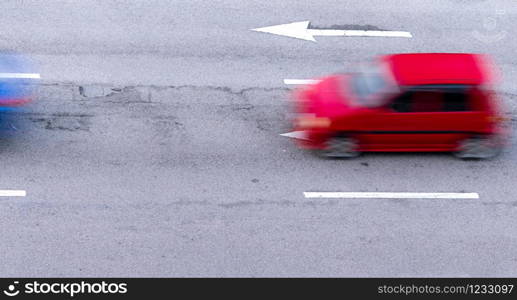 Red and blue car fast moving on asphalt road in the city. Blurred motion of fast speed compact car on asphalt road. Urban transport with rush hour concept. Travel by car. Car fuel consumption concept.