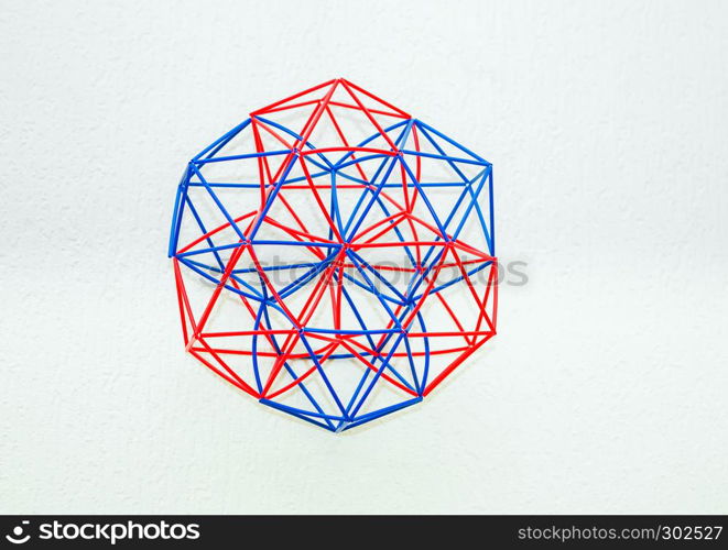 Red and blue handmade three-dimensional model of geometric solid on a white textured background.. Coloured Handmade Dimensional Model Of Geometric Solid