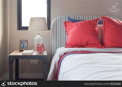 Red and blue pillows on the cozy bed with striped headboard
