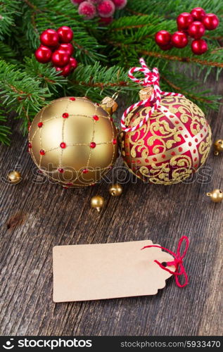 red and golden christmas balls on wooden background with empty tag. red and golden christmas balls