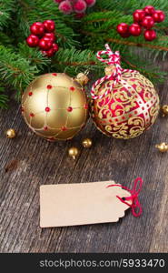 red and golden christmas balls on wooden background with empty tag. red and golden christmas balls