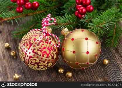 red and golden christmas balls with evergreen tree on wooden background. red and golden christmas balls