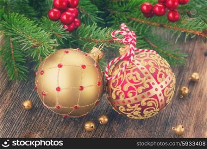 red and golden christmas balls with evergreen tree on wooden background, retro toned