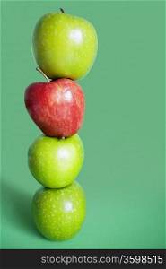 Red and green apples balancing over colored background