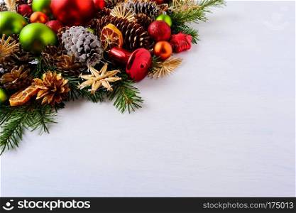 Red and green Christmas ornaments, fir branches and pine cones. Christmas decoration with jingle bell and dried orange slices. Christmas greeting background. Copy space.