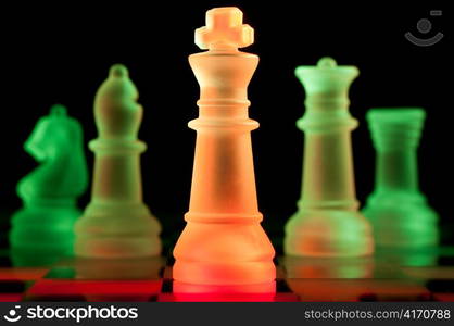 red and green glass chess pieces is standing on board in dark