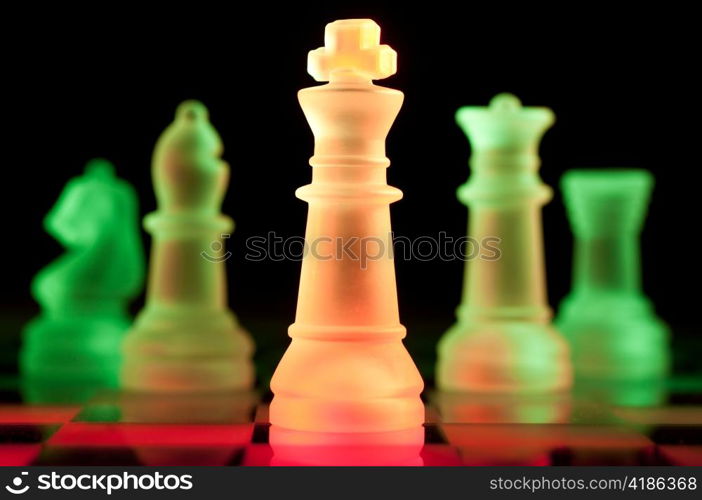 red and green glass chess pieces is standing on board in dark