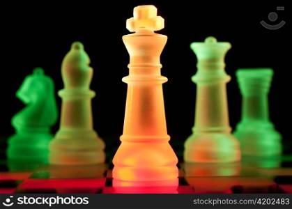 red and green glass chess pieces is standing on board in dark