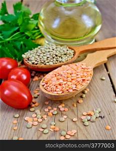 Red and green lentils in a wooden spoon, tomatoes, parsley, vegetable oil in a carafe on the background of wooden boards