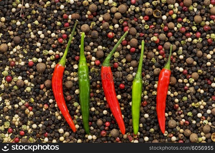 Red and green peppers on pepper background