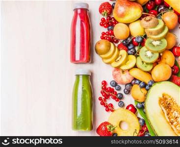 Red and green smoothies and juices beverages in bottles with various fresh organic fruits and berries ingredients on white wooden background, top view. Healthy food and vegetarian concept