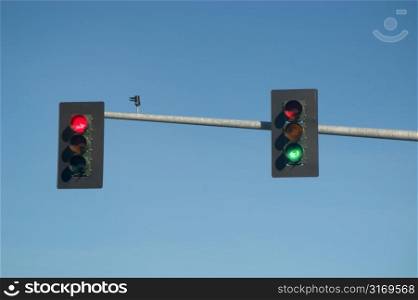 Red And Green Traffic Lights Hanging In A Clear Blue Sky