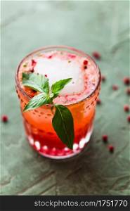 Red and pink drink garnished with an ice cube and basil
