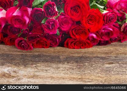 red and pink fresh roses  on wooden table border  . Border of red roses 