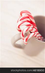 Red and white candy canes in a cup on a gray wooden background