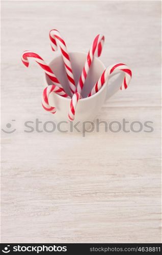 Red and white candy canes in a cup on a gray wooden background