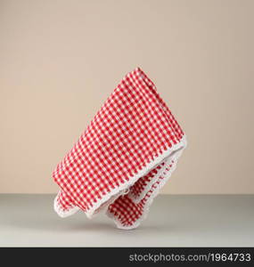 red and white checkered kitchen towel levitates on beige gray background