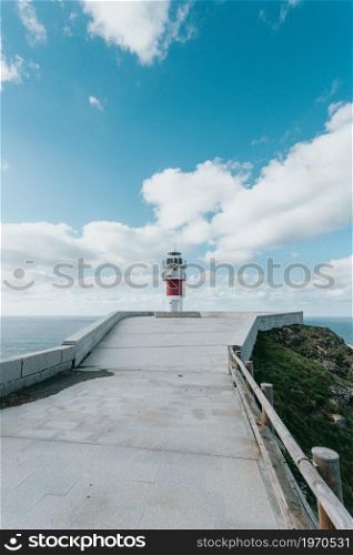 Red and white lighthouse in the coast of spain during a clear day with copy space , relax and inspiration concept