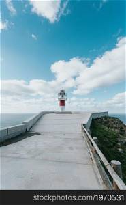 Red and white lighthouse in the coast of spain during a clear day with copy space , relax and inspiration concept