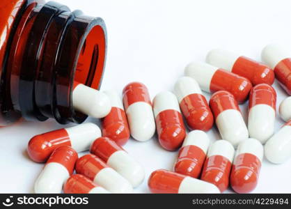 Red-and-white medicine capsules from a bottle