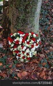red and white sympathy floral arrangement near a tree