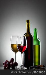 Red and white wine in glasses with grape and bottles