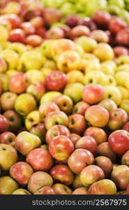 Red and yellow apples piled on table at produce market.