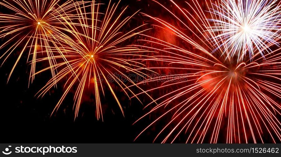 Red and yellow fireworks bursting on dark night sky background. Fireworks widescreen
